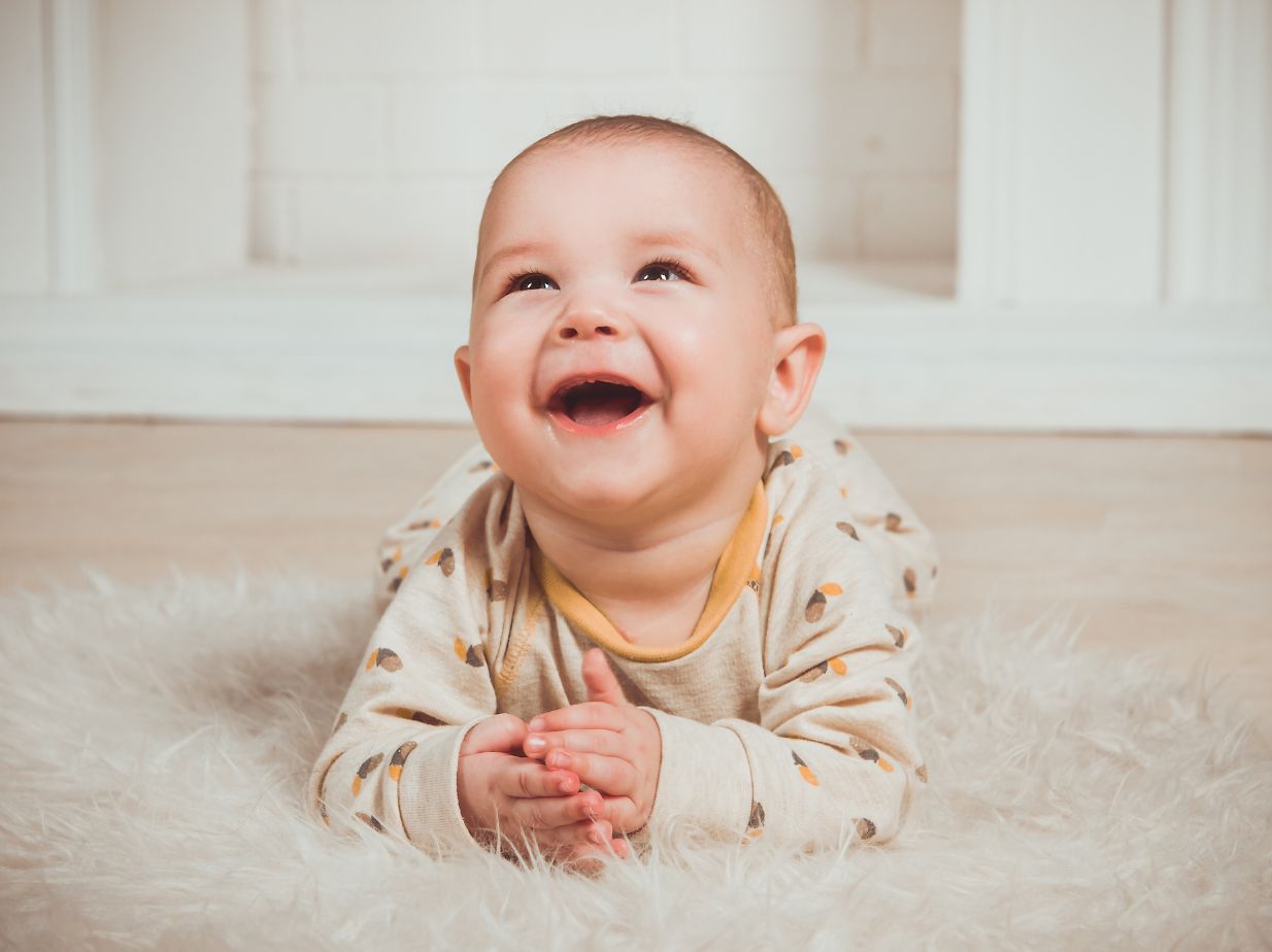 Niño gateando y sonriendo en una habitación con alfombra