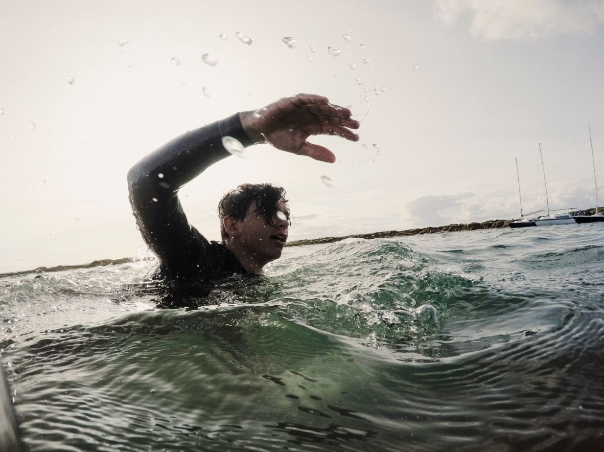 Hombre nadando en la playa, con una marea complicada