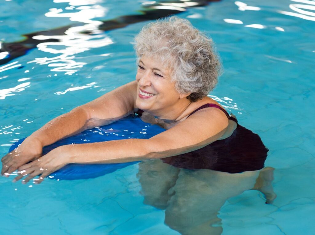 Mujer mayor haciendo ejercicio en la alberca y disfrutando de los beneficios de la natación para adultos mayores