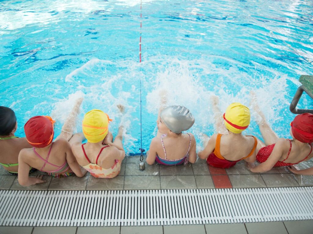 Niños pataleando en la orilla de una piscina 