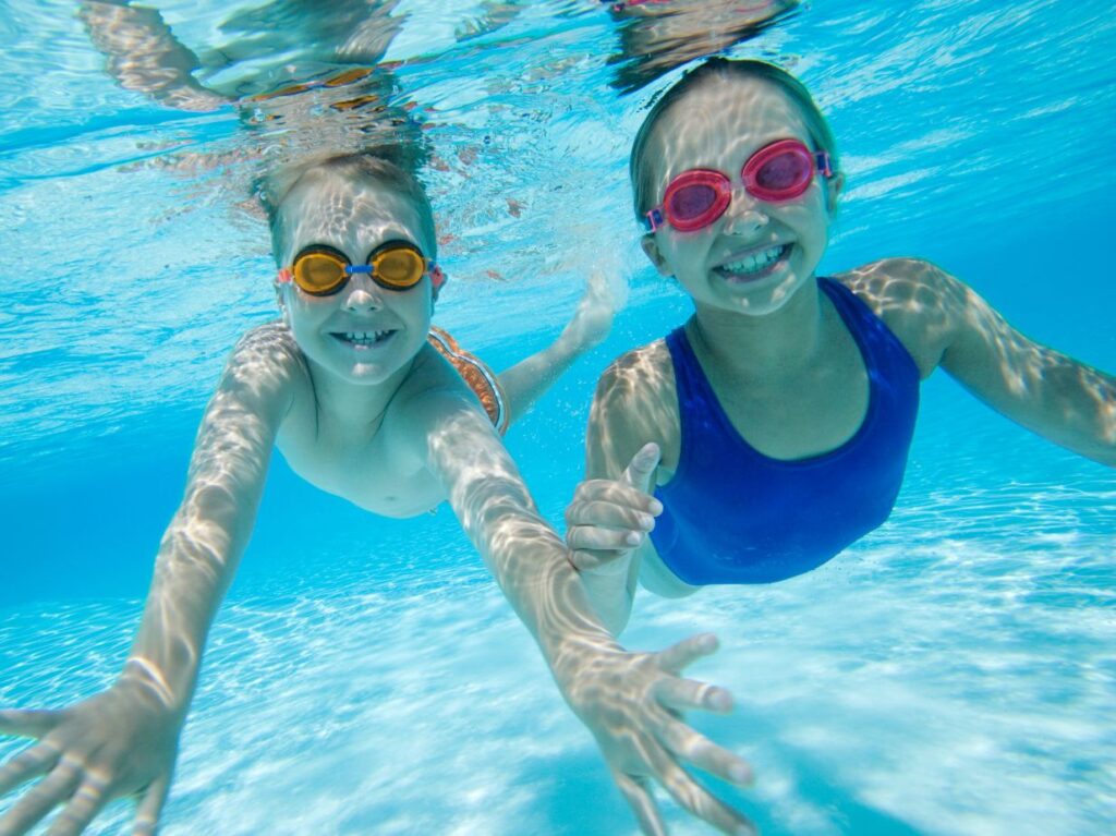 Niños sonrientes debajo de una pisicina