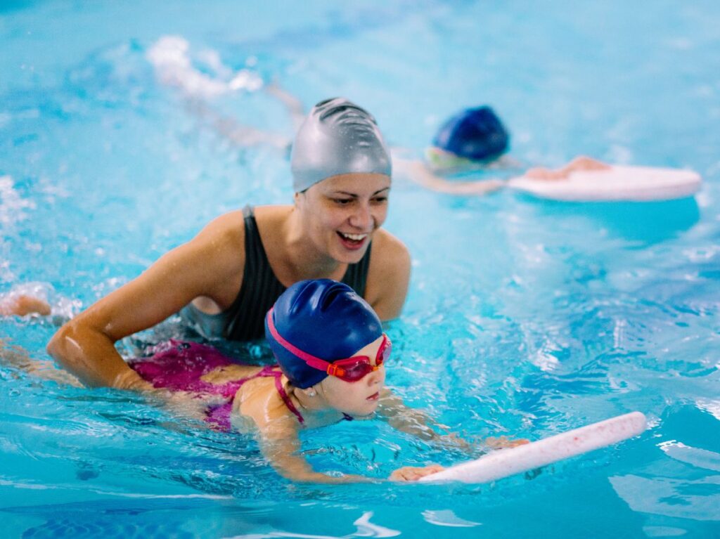 Una maestra de natación enseñando a nadar a una niña