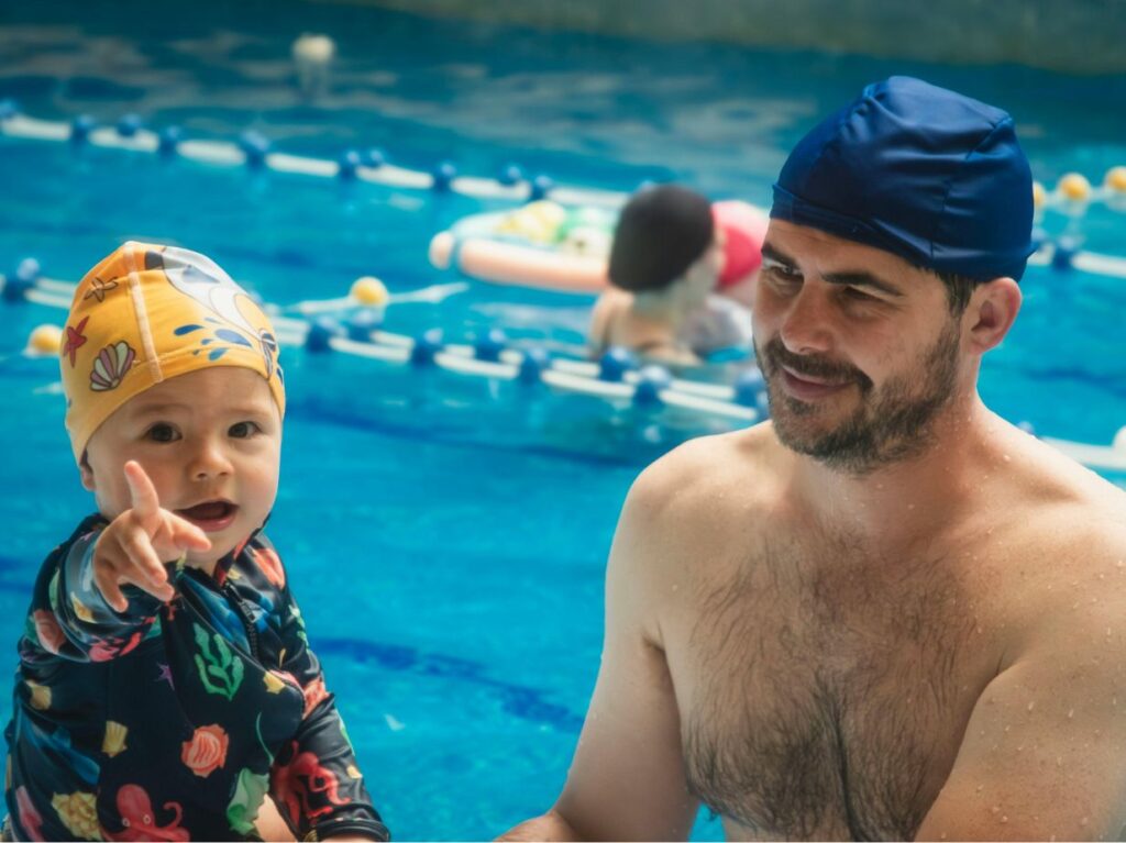 Un padre observando a su bebé nadar
