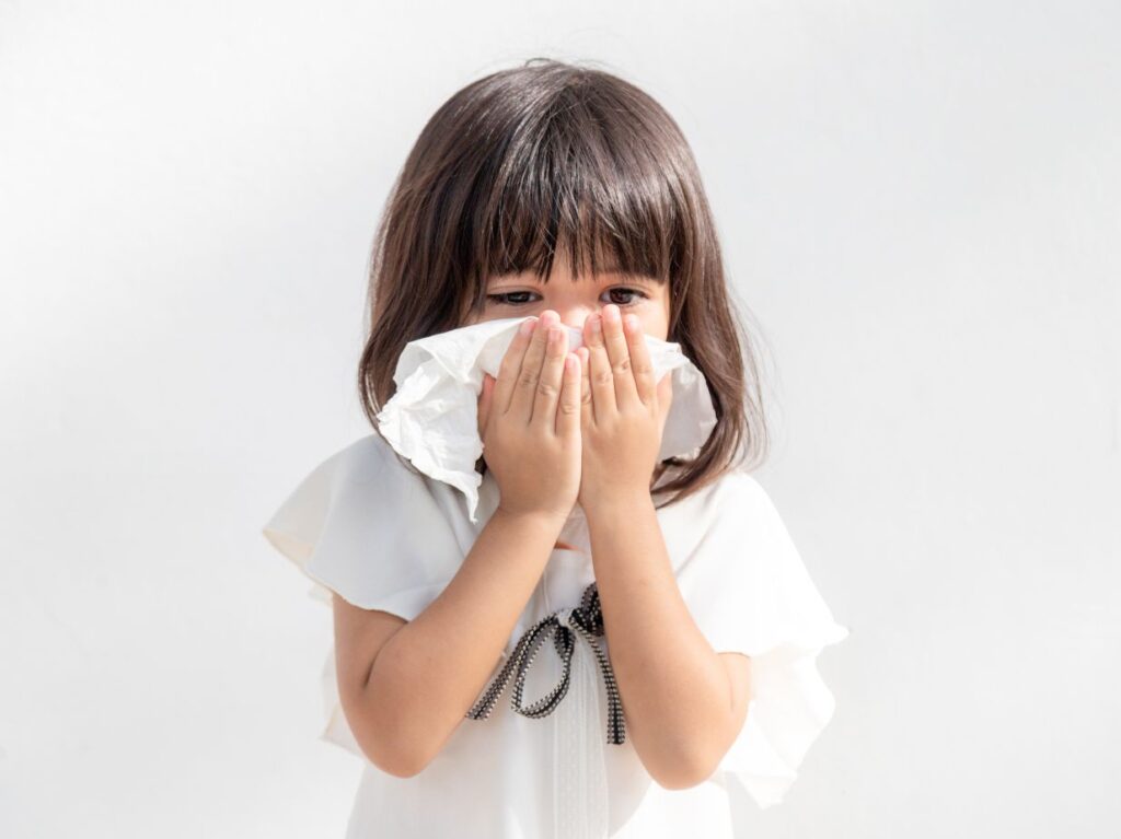 Una niña resfriada, sonándose la nariz