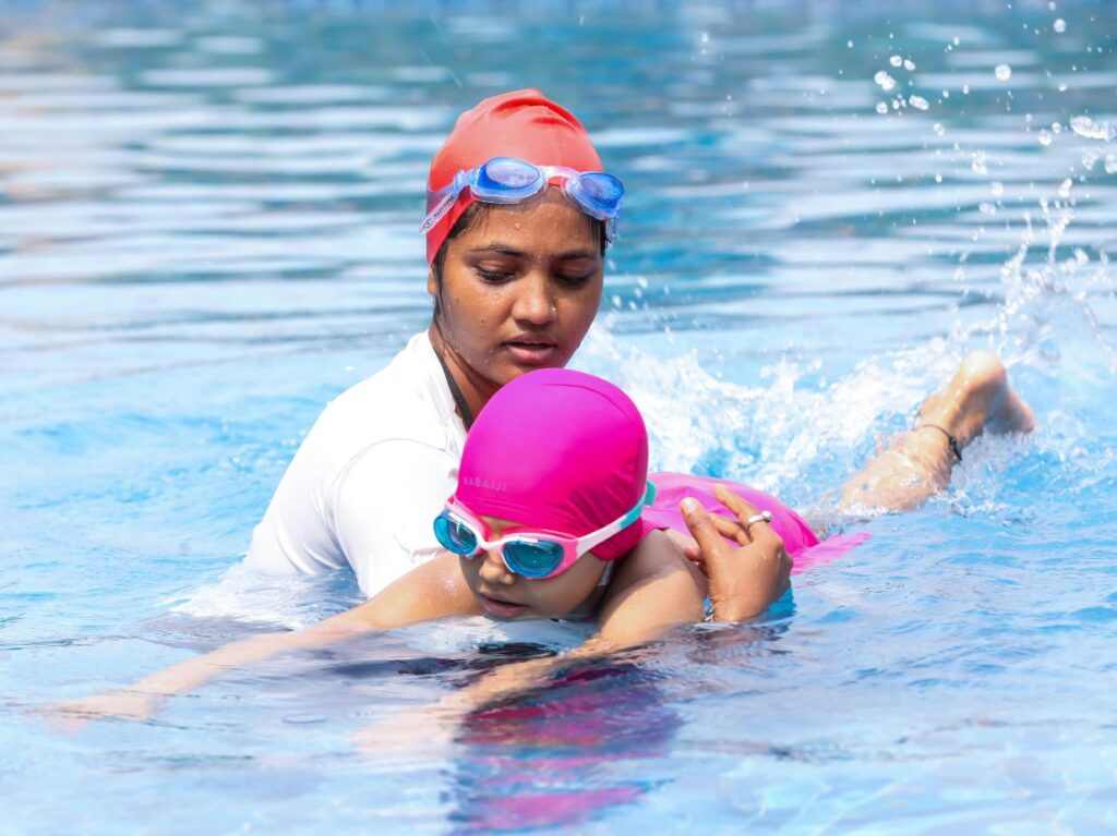 Una maestra enseñando a nadar a una niña