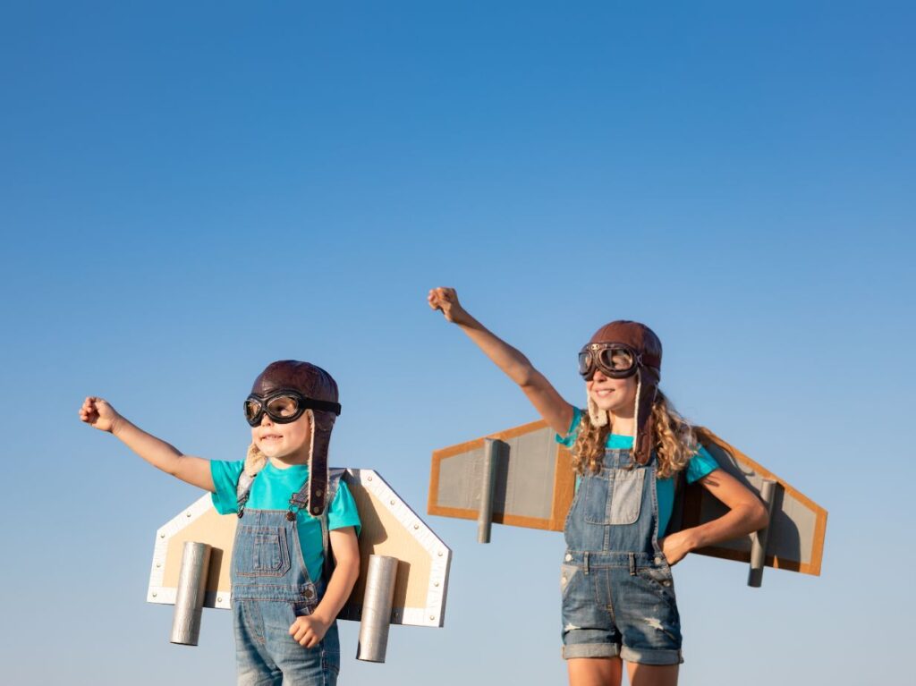 Dos niños disfrazados de aviones como si estuviesen volando