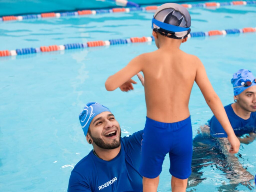 Un niño entrando a una piscina con su coach