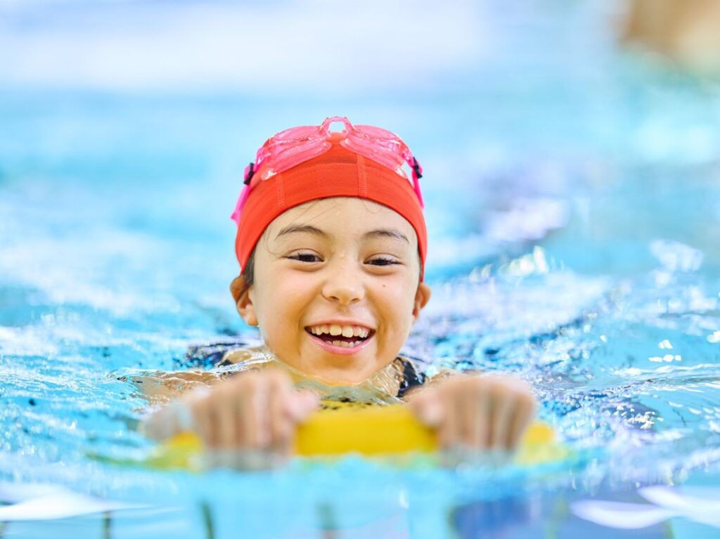 Niño practicando natación, una actividad que es ideal para acompañar el desarrollo emocional y conductual de los niños