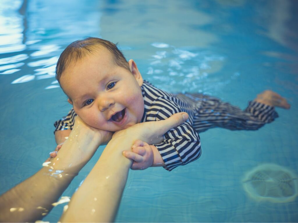 Bebé nadando con la ayuda de su padre